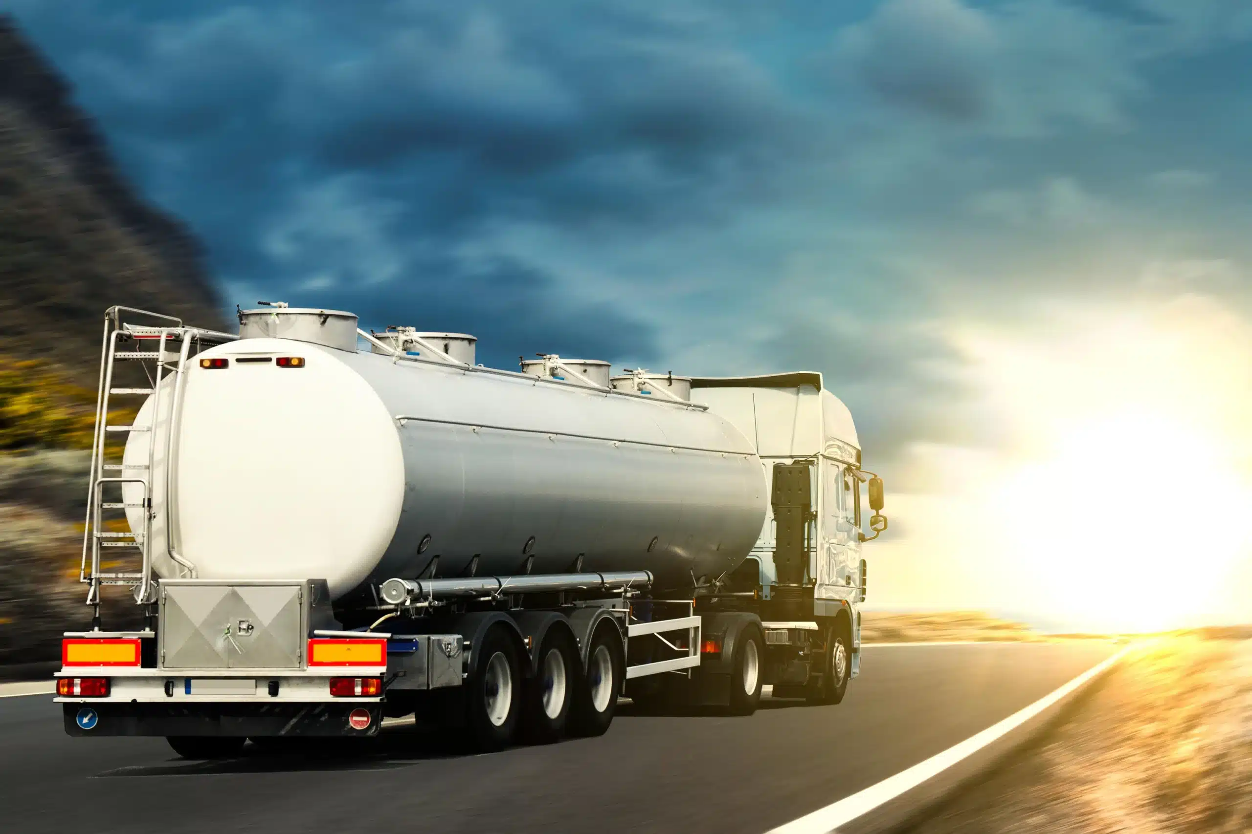 Bulk fuel tanker truck on highway at sunset