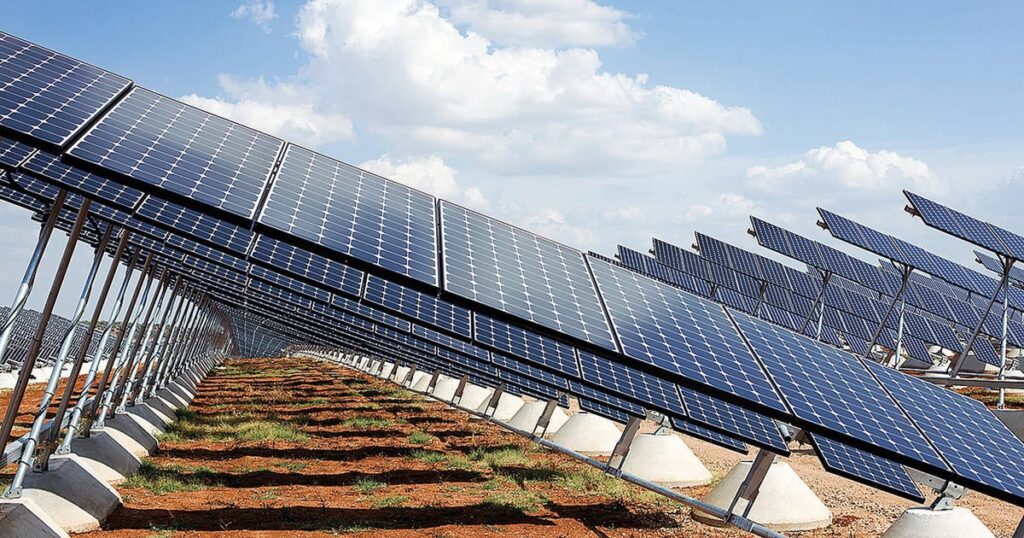 A large photovoltaic power station with rows of solar panels tilted toward the sun