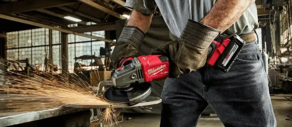 Worker using fuel powered tools, cutting metal with visible sparks in an industrial workshop